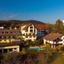 Luftaufnahme eines Dorfes mit einem Hotel, einem Pool und einer Kirche im Hintergrund.
