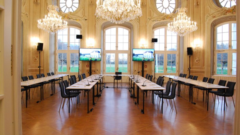 Eleganter Konferenzraum mit Kronleuchtern und gro&szlig;en Fenstern.