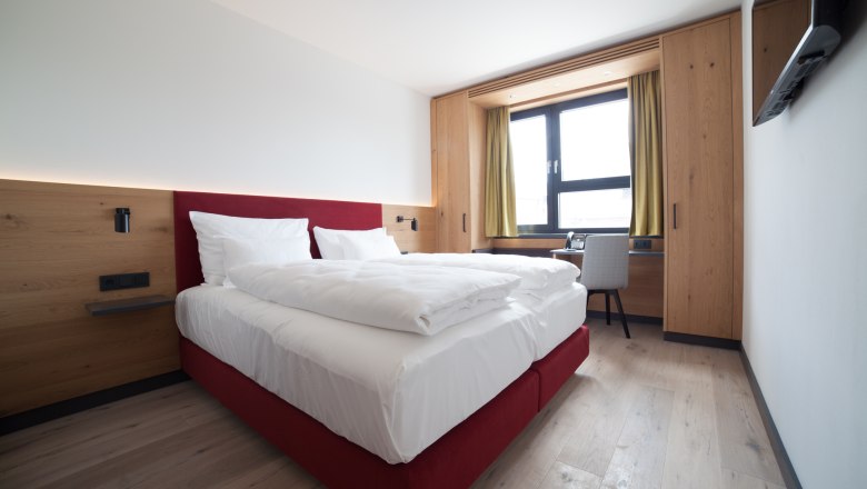 Doppelbett in hellem Zimmer mit Fenster