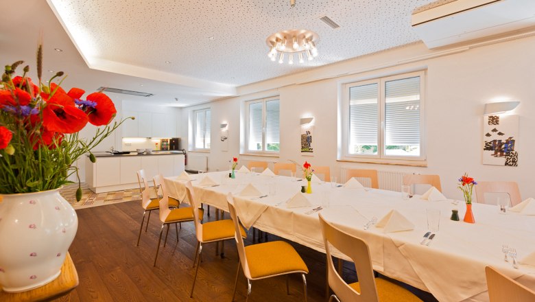 Ein heller Raum mit gedecktem Tisch und Showk&uuml;che im Hintergrund.