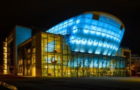 Festspielhaus St. Pölten bei Nacht, beleuchtet in Blau und Gelb.