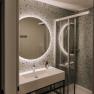 Modernes Badezimmer mit beleuchtetem Spiegel und Dusche.