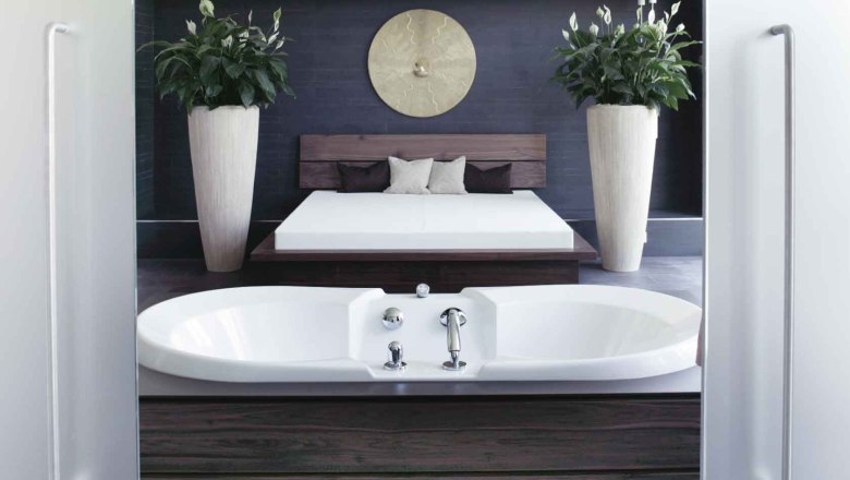 Moderner Spa-Bereich mit Badewanne, Bett und Pflanzen.