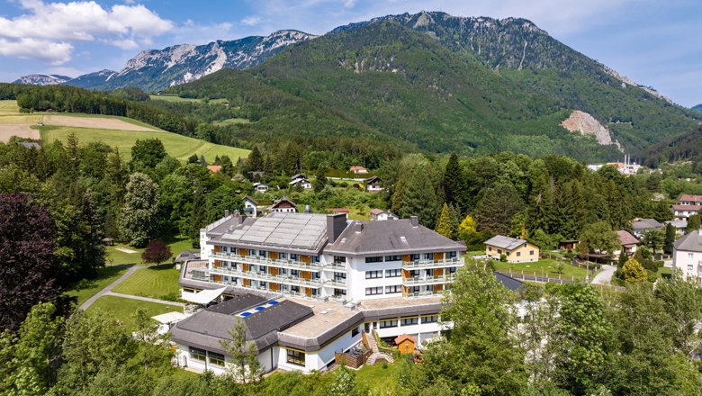 Luftaufnahme eines gro&szlig;en Hotels in einer gr&uuml;nen, bergigen Landschaft.