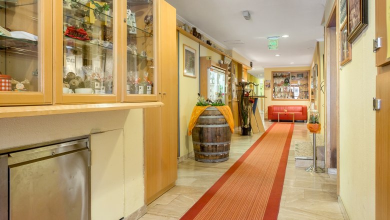 Ein Hotelkorridor mit rotem Teppich, Vitrinen und Dekorationen.