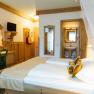 Gemütliches Hotelzimmer mit Doppelbett, Holzmöbeln und kleinem Badezimmer.