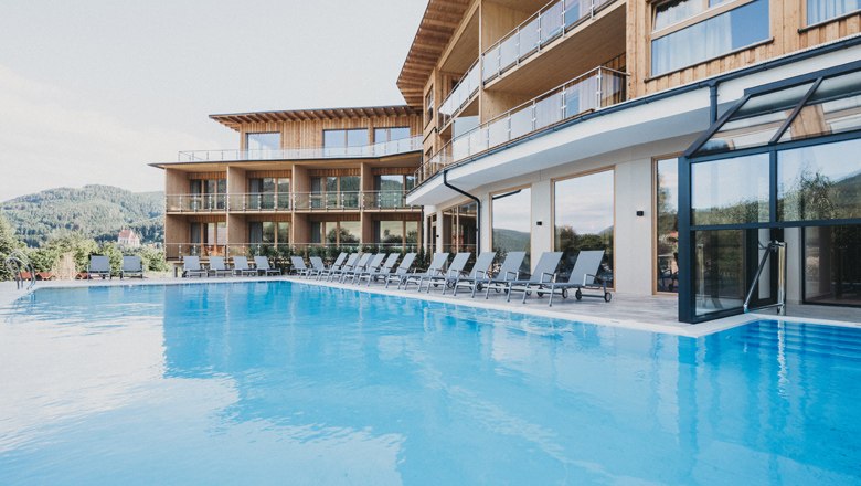 Modernes Hotel mit Pool und Liegestühlen im Freien.