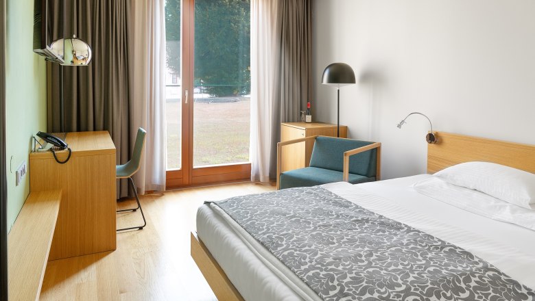 Modernes Hotelzimmer mit Holzmöbeln, großem Fenster und Bett.