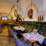 Elegantes Restaurant mit gedeckten Tischen, dekorativen Elementen und Weinflaschen auf einem Regal.