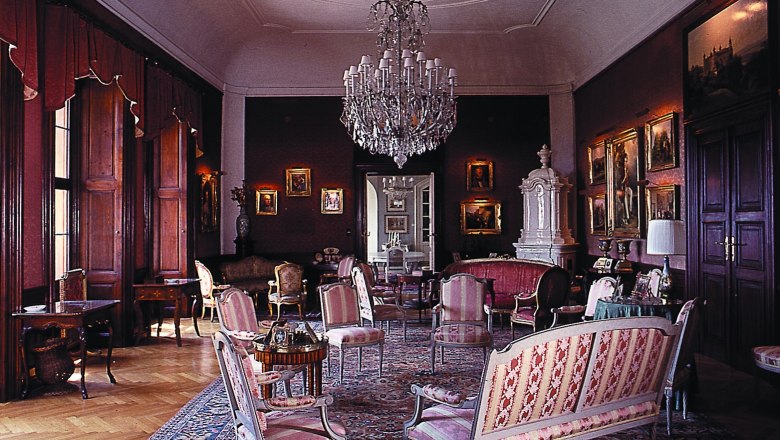 Eleganter Salon mit antiken Möbeln, Kronleuchter und Gemälden.