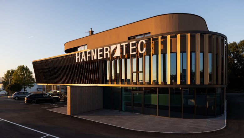 Modernes Geb&auml;ude mit der Aufschrift 'HAFNER TEC' bei Sonnenuntergang.