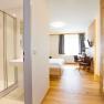 Modernes Hotelzimmer mit Bad, Bett, Schreibtisch und St&uuml;hlen.