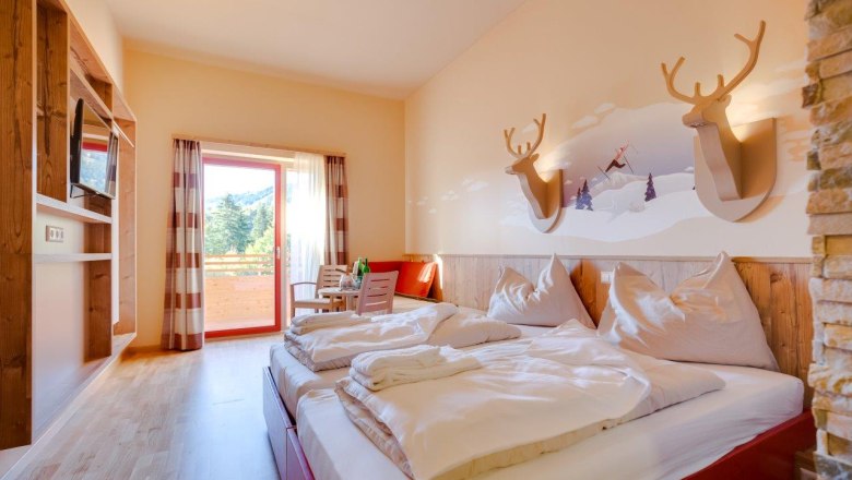Hotelzimmer mit Doppelbett, Holzm&ouml;beln und Balkon mit Bergblick.