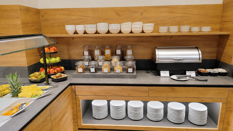 Fr&uuml;hst&uuml;cksbuffet mit Obst, M&uuml;sli und Geschirr in einem Hotelrestaurant.