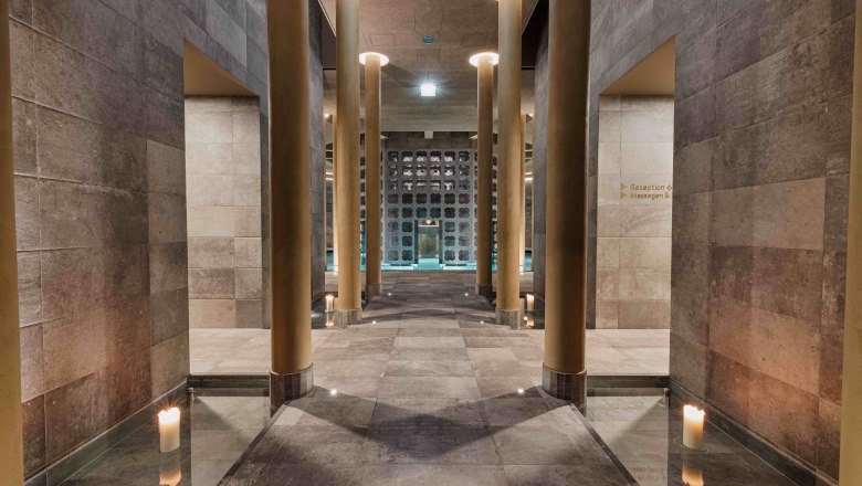 Innenansicht eines modernen Spas mit hohen S&auml;ulen und Kerzenlicht.