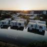 Luftaufnahme von modernen Geb&auml;uden am Wasser im Thermenresort Laa bei Sonnenuntergang.