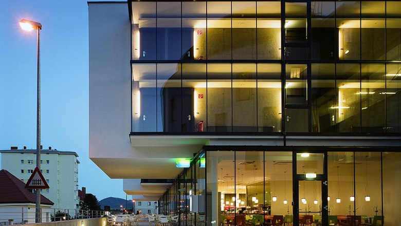 Modernes Hotelgebäude mit Glasfassade bei Dämmerung.