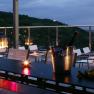 Abendliche Terrasse mit Kerzenlicht, Weingl&auml;sern und Blick auf eine Stadt.