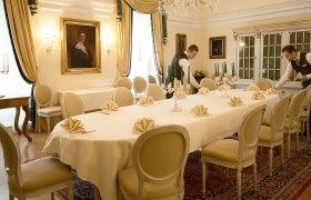 Eleganter Speisesaal mit gedecktem Tisch, Kerzenleuchtern und zwei Kellnern.