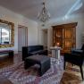 Elegantes Wohnzimmer mit antikem Schrank, gro&szlig;em Spiegel, schwarzen Lederm&ouml;beln und einem Kronleuchter.