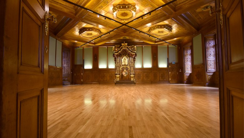 Innenansicht des Rittersaals im Palais Niederösterreich mit Holzboden und kunstvoller Holzdecke.