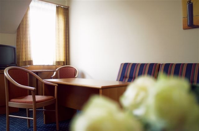 Hotelzimmer mit Tisch, St&uuml;hlen und Sofa.