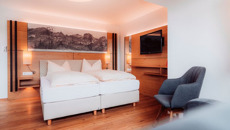 Modernes Hotelzimmer mit Doppelbett, Holzboden und Wanddekoration.