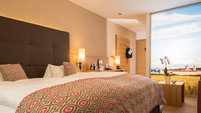 Modernes Hotelzimmer mit Doppelbett, stilvollen Lampen und großem Fenster mit Landschaftsansicht.