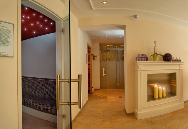 Ein eleganter Wellnessbereich mit Kamin, Kerzen und Sauna.