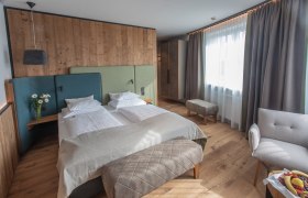 Modernes Hotelzimmer mit Doppelbett, Holzwänden und großen Fenstern.
