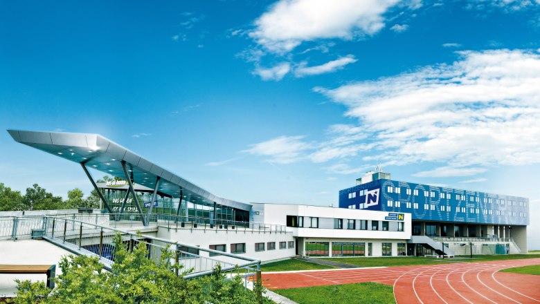 Modernes Sportzentrum mit Laufbahn und blauen Himmel.