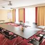 Konferenzraum mit U-f&ouml;rmigem Tisch, St&uuml;hlen, Flipchart und Projektor.