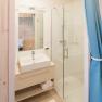 Modernes Badezimmer mit Waschbecken, Spiegel, Dusche und blauen Vorh&auml;ngen.