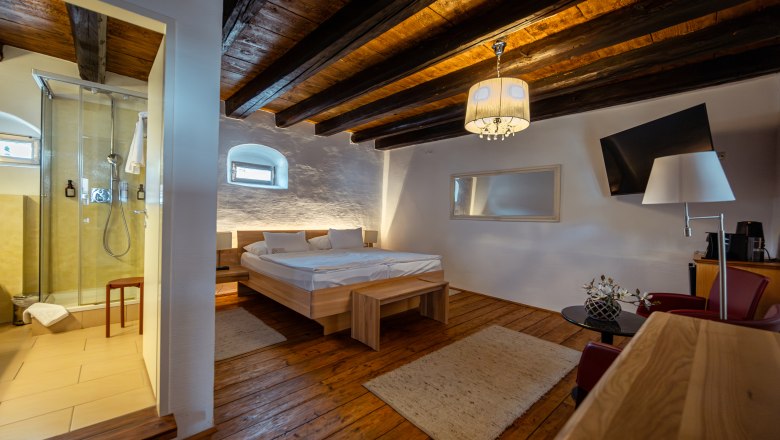 Gem&uuml;tliches Zimmer mit Holzboden, Doppelbett, Dusche und moderner Einrichtung.