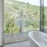 Badezimmer mit freistehender Badewanne und Blick auf Weinberge.
