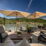 Terrasse mit Blick auf die Donau und umliegende H&uuml;gel, ausgestattet mit Sonnenschirmen und Sitzm&ouml;beln.