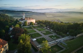 Luftaufnahme der Schallaburg mit Gartenanlage und umliegender Landschaft.