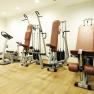 Ein Fitnessraum mit Laufband, Heimtrainer und Kraftger&auml;ten auf Holzboden.