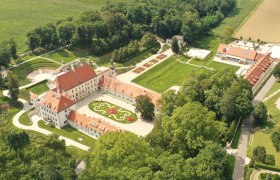 Luftaufnahme von Schloss Thalheim mit umliegenden Gärten und Gebäuden.