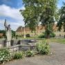 Blick auf eine historische Schlossanlage mit Statue und Garten.