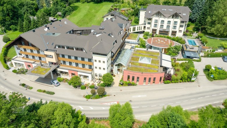 Luftaufnahme eines großen Hotelkomplexes mit mehreren Gebäuden, umgeben von grüner Landschaft.