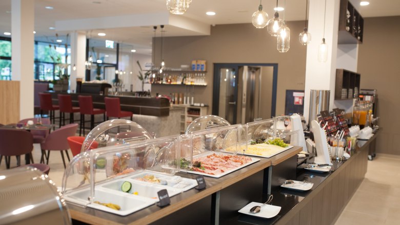 Fr&uuml;hst&uuml;cksraum mit mehreren Tischen und Fr&uuml;hst&uuml;cksbuffet