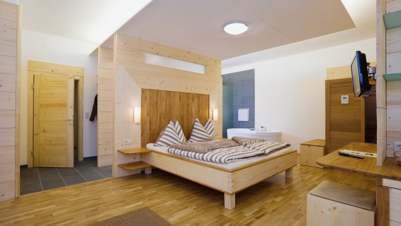 Holzinterieur eines modernen Hotelzimmers mit Doppelbett und Badewanne.