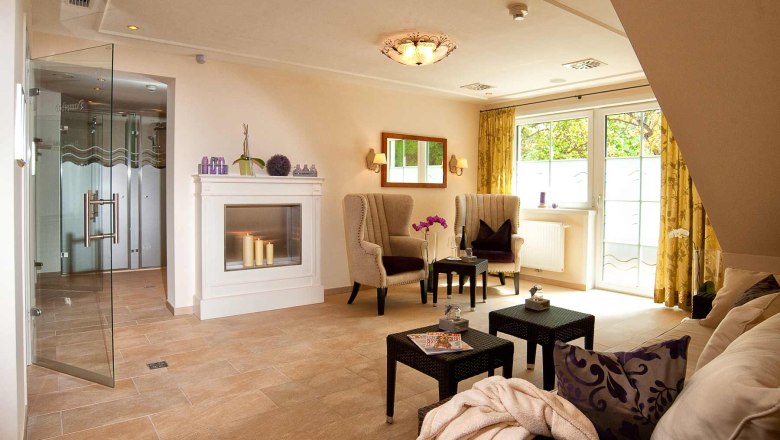 Eleganter Wellnessbereich mit Kamin, Sesseln und Glast&uuml;r.