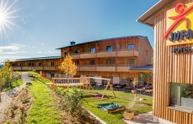JUFA Hotel Annaberg mit Spielplatz und sonnigem Himmel.