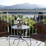 Zwei Rattanst&uuml;hle und ein Tisch mit Sektk&uuml;hler auf einer Terrasse mit Bergblick.