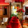 Elegantes Restaurant mit roten Samtst&uuml;hlen, Kronleuchter und Blumendekoration.