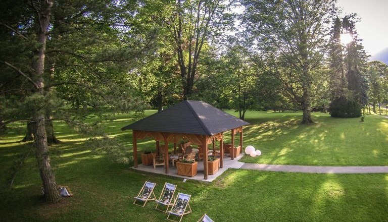 Ein Pavillon im Park mit Liegest&uuml;hlen und B&auml;umen.