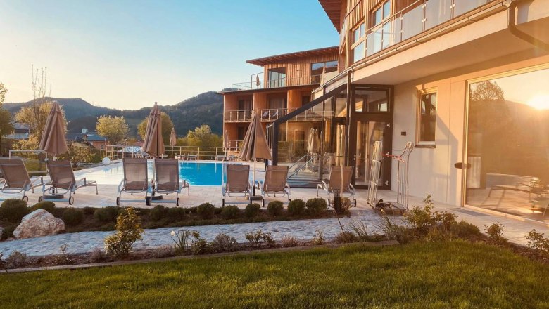 Au&szlig;enbereich des Naturhotel Molzbachhof mit Pool und Liegest&uuml;hlen bei Sonnenuntergang.