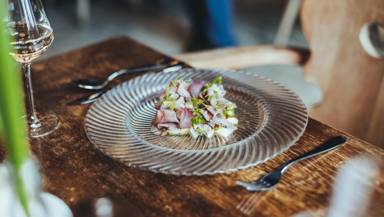 Ein Teller mit Roastbeef und Spargelsalat auf einem Holztisch, daneben ein Glas Wei&szlig;wein.